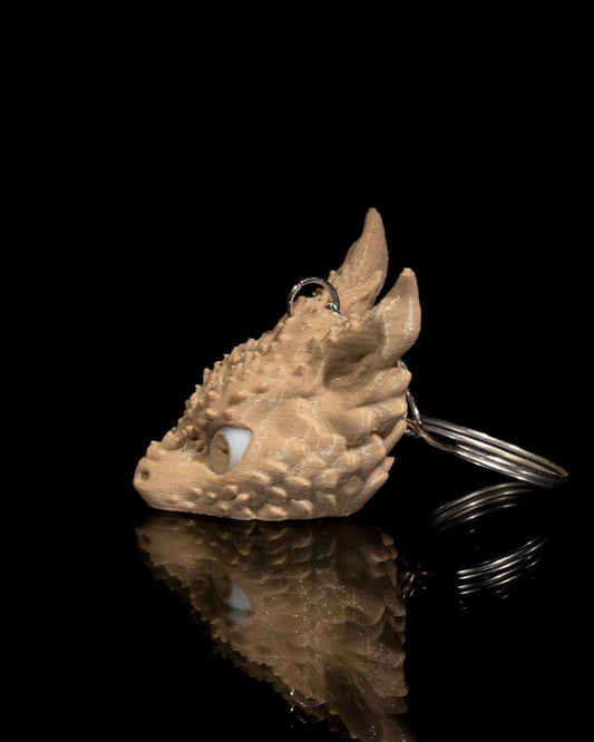 a keychain shaped like a dragon's head on a reflective surface