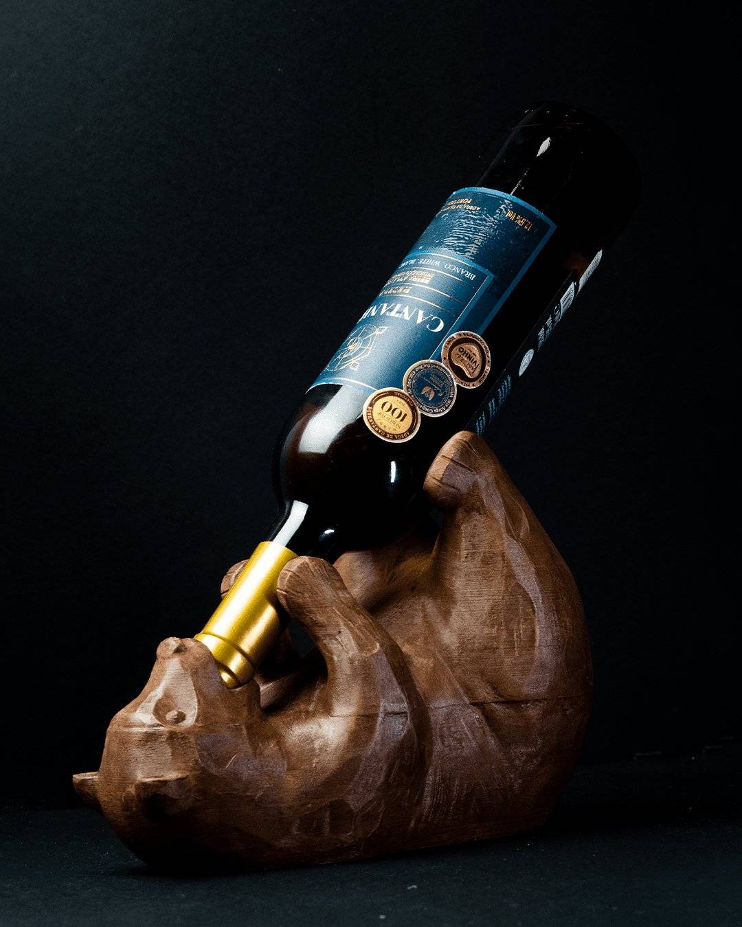 a wooden bear holding a bottle of wine