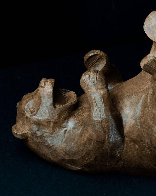 a wooden sculpture of a rhino laying down