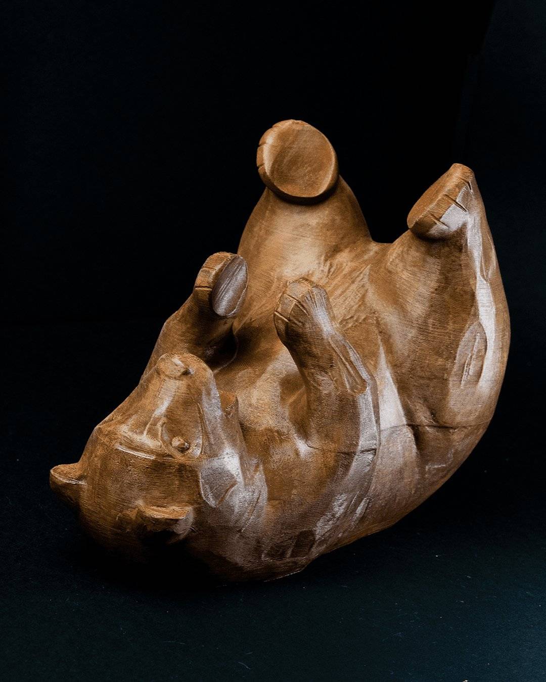 a wooden sculpture of a rhino on a black background
