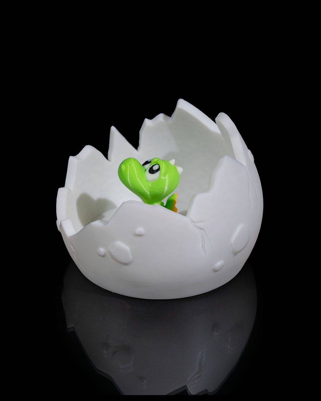 a small green toy in a white egg shell