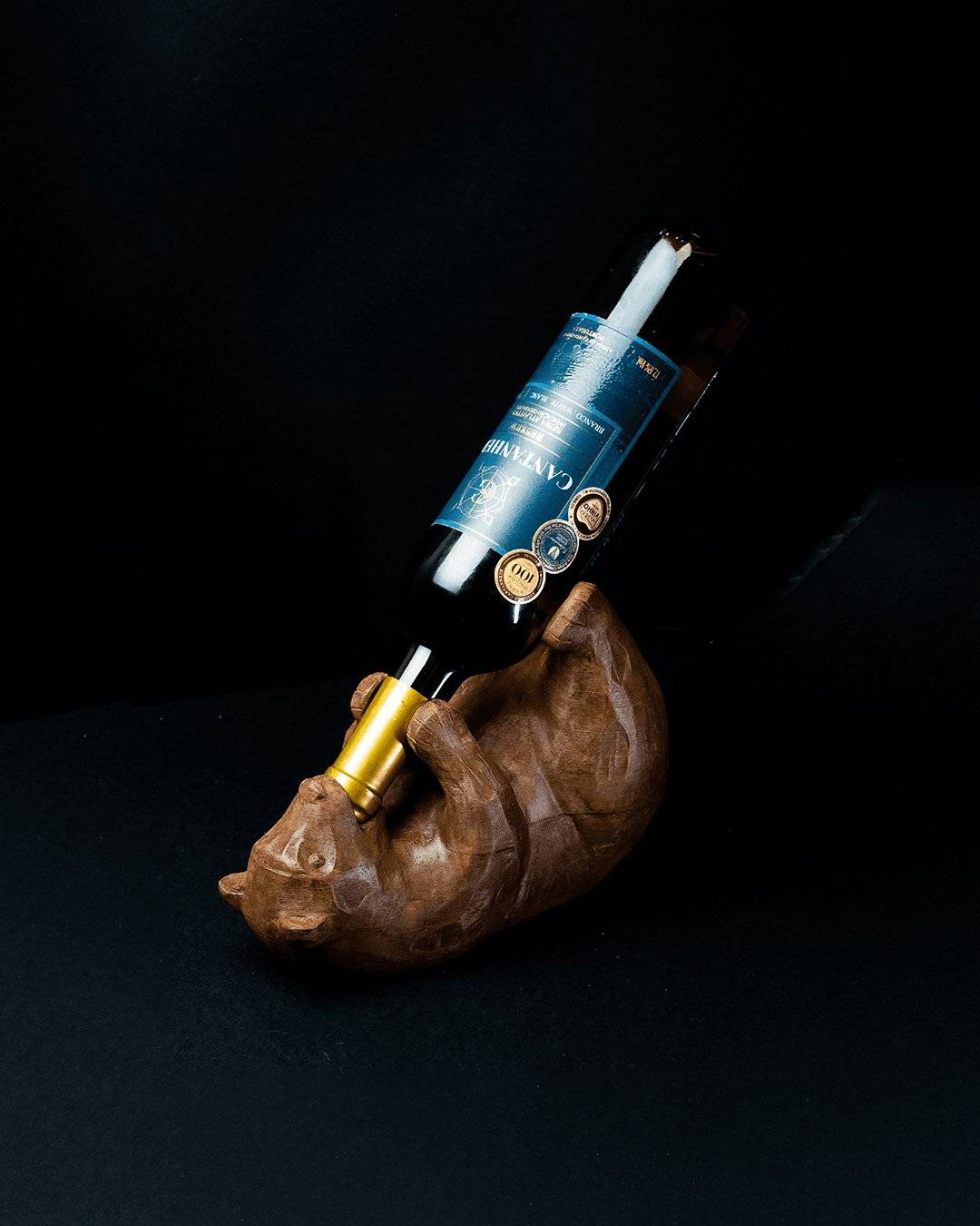 a wooden sculpture of a bear holding a bottle of wine